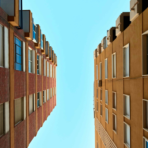 low-angle-shot-apartment-buildings-against-clear-sky-background-min low-angle-shot-apartment-buildings-against-clear-sky-background-min